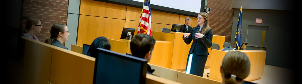 A Dickinson Law student addresses a jury, with a judge looking on from the bench, as part of mock trial exercises in a courtroom.