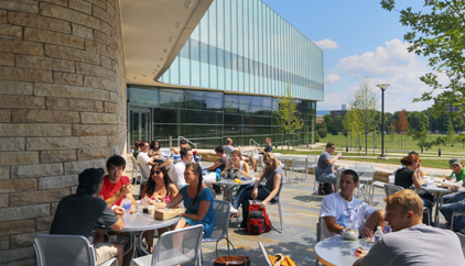 People sit at tables on a patio outside Lewis Katz Building, Penn State Law, University Park campus